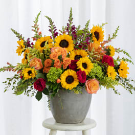 Mixed bouquet of sunflowers and roses in a gray vase