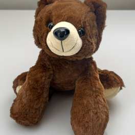 Brown plush teddy bear seated on a white surface