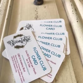 Stack of flower club cards on a wooden surface