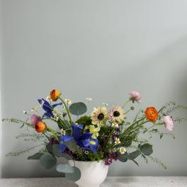Mixed bouquet in a white vase with blue and orange blooms