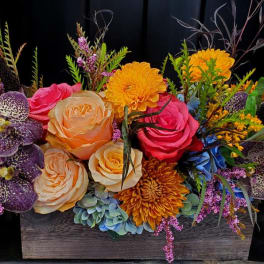 Colorful floral arrangement in a wooden box with roses and orchids