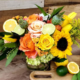 Bouquet of roses and sunflowers with citrus slices in a glass vase