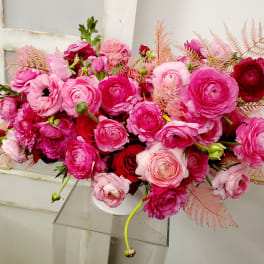 Pink and red ranunculus bouquet in a white vase