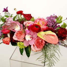 Mixed bouquet of pink, red, and purple flowers in a clear vase