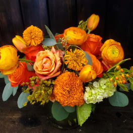 Orange and yellow flower arrangement in a black vase