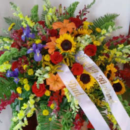 Large standing floral spray with sunflowers, roses, and ribbons