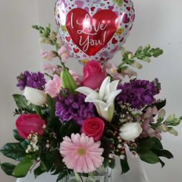 Mixed flower arrangement with a heart-shaped "I Love You" balloon in a glass vase