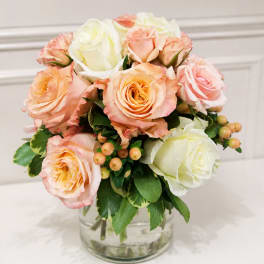 Peach and white roses arranged in a clear glass vase