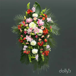Standing floral spray with pink, white, and red blooms on a dark background