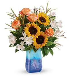 Sunflowers and peach roses in a blue glass vase