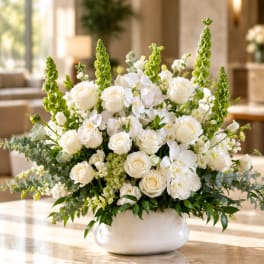 White roses and orchids arranged in a white bowl vase