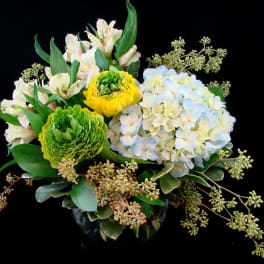 Bouquet of white alstroemeria, green and yellow blooms, and pale blue hydrangea in a vase