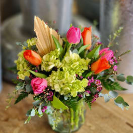 Bouquet of pink and orange tulips with green hydrangeas in a glass vase