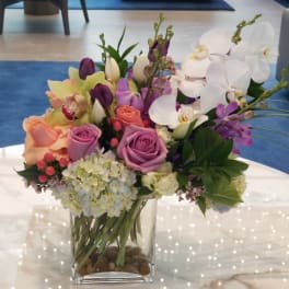 Mixed bouquet of roses, orchids, tulips, and hydrangeas in a glass vase