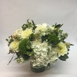 White and pale yellow floral arrangement in a round container