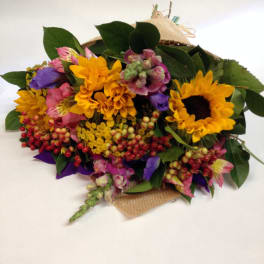 Mixed bouquet with sunflowers, pink blooms, and berries wrapped in burlap