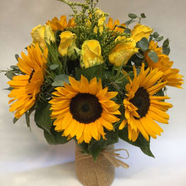 Bouquet of yellow roses and sunflowers in a burlap-wrapped vase