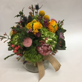 Mixed bouquet in a glass vase with yellow, pink, and purple blooms