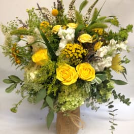 Yellow roses and white flowers in a burlap-wrapped vase