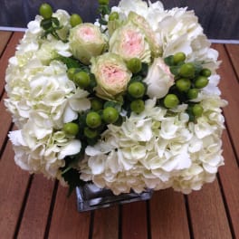 White hydrangea and pale pink roses in a square glass vase