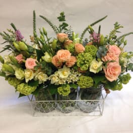 Mixed bouquet of peach roses and white blooms in glass jars