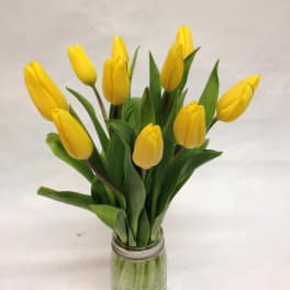 Yellow tulips arranged in a clear glass jar