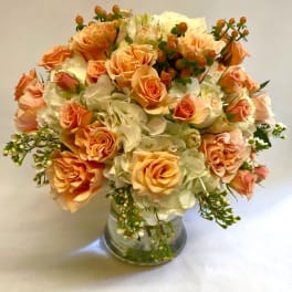 Peach roses and white hydrangeas in a clear glass vase