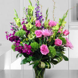 Tall bouquet of pink and purple flowers in a clear glass vase