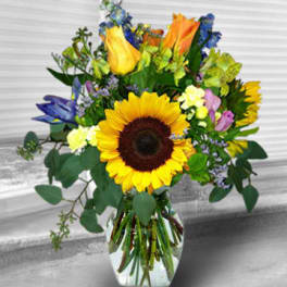 Mixed bouquet with a sunflower and orange roses in a glass vase