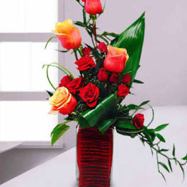 Red and orange roses arranged in a tall glass vase