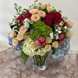Mixed bouquet of roses and hydrangeas in a clear glass vase