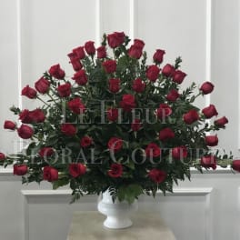 Large arrangement of red roses in a white pedestal vase