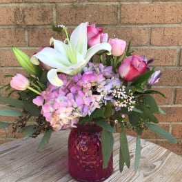 Pink and white floral arrangement in a magenta vase