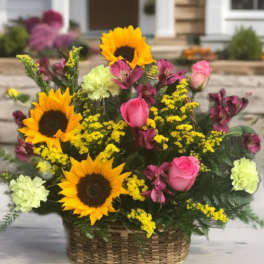 Basket arrangement with sunflowers, pink roses, and yellow filler flowers