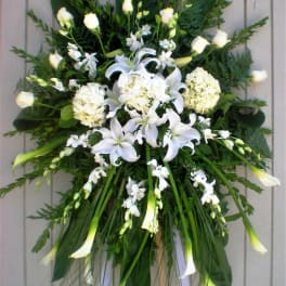 White floral standing spray with lilies, roses, and orchids