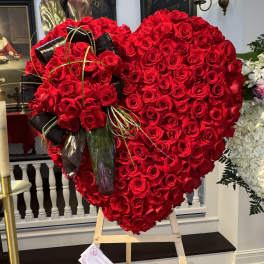 Heart-shaped red rose arrangement on an easel with black ribbon accents