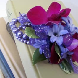 Purple floral corsage with beads on a book stack
