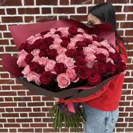 Large bouquet of pink and red roses wrapped in burgundy paper