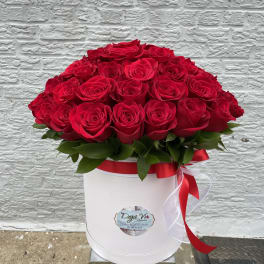Red roses arranged in a white hat box with a red ribbon