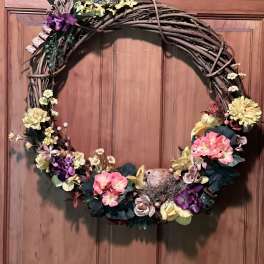 Floral wreath with pink, yellow, and purple flowers on a twig frame