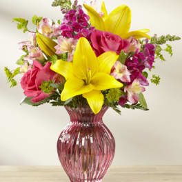 Pink roses and yellow lilies in a pink glass vase