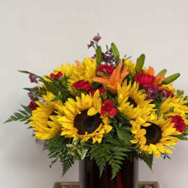 Bouquet of sunflowers, red roses, and orange lilies in a dark vase