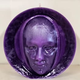 Purple decorative mask sculpture with a face in the center