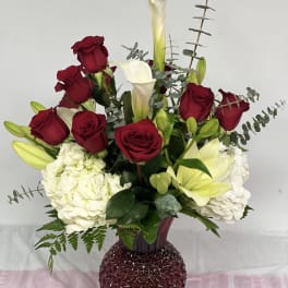Red roses and white calla lilies in a burgundy vase