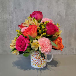 Bright mixed bouquet in a patterned mug vase