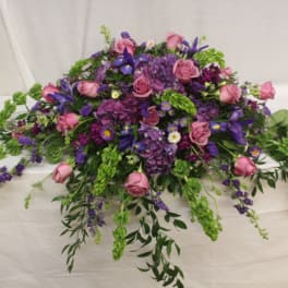 Large purple and pink floral arrangement with trailing greenery
