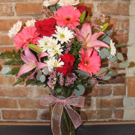 Pink and red mixed bouquet in a glass vase with a ribbon