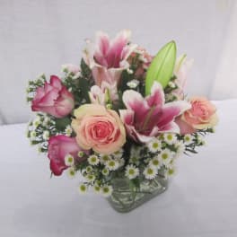 Pink roses and lilies arranged in a clear glass vase