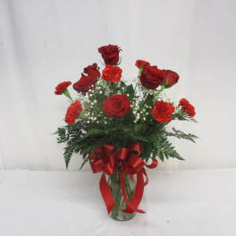 Red roses and carnations in a glass vase with a red ribbon
