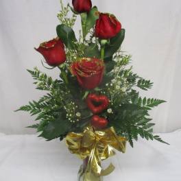 Red roses in a glass vase with a gold bow and glittery heart accents
